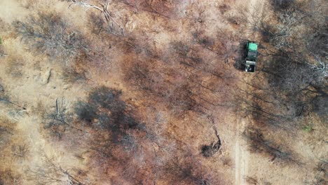 Vista-Aérea-De-Un-Vehículo-De-Cuatro-Ruedas-Conduciendo-Por-El-Sendero-Arenoso-En-El-Desierto-De-Kalahari,-áfrica---Toma-Aérea-De-Drones