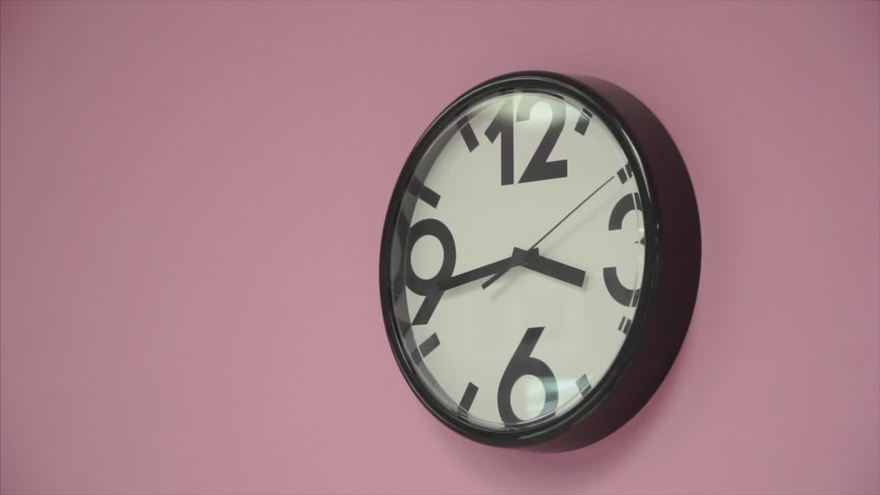 reloj de pared negro en una pared rosa