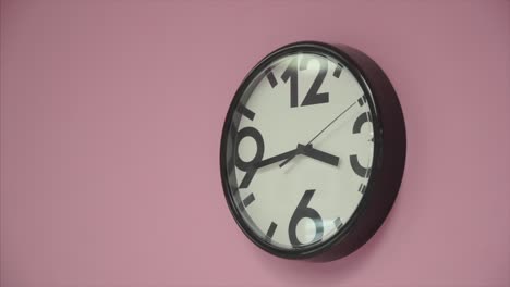 black wall clock on a pink wall