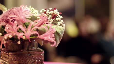 ramo de flores de pie sobre una mesa con gente en el fondo