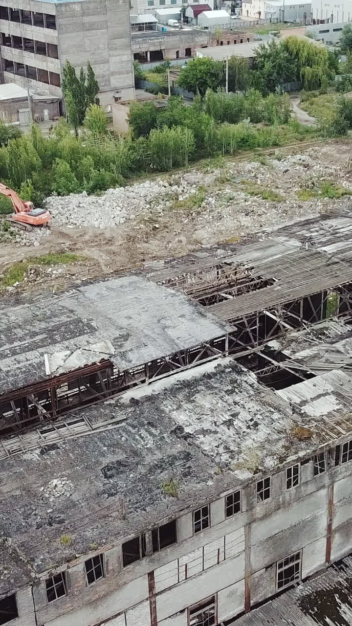 Flying over abandoned industrial factory buildings in very dilapidated condition. Old building for demolition.. Vertical video