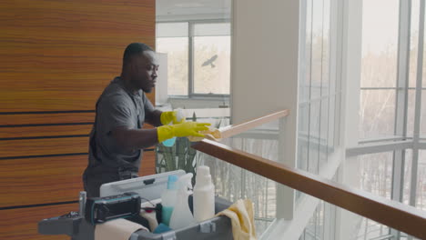 cleaning man cleaning stair railing inside an office building while dancing