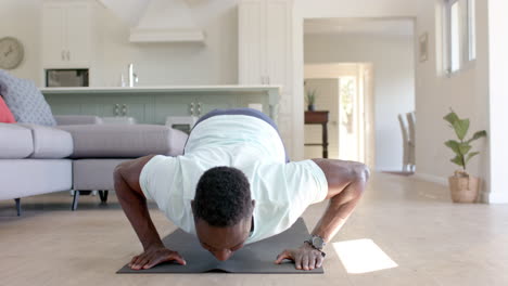 Hombre-Afroamericano-Enfocado-Haciendo-Flexiones-En-Una-Sala-De-Estar-Soleada,-Cámara-Lenta