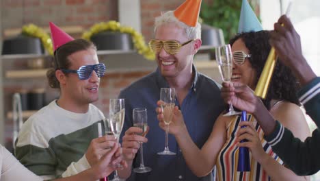 Happy-group-of-diverse-friends-in-party-hats-celebrating-together,-toasting-with-vine