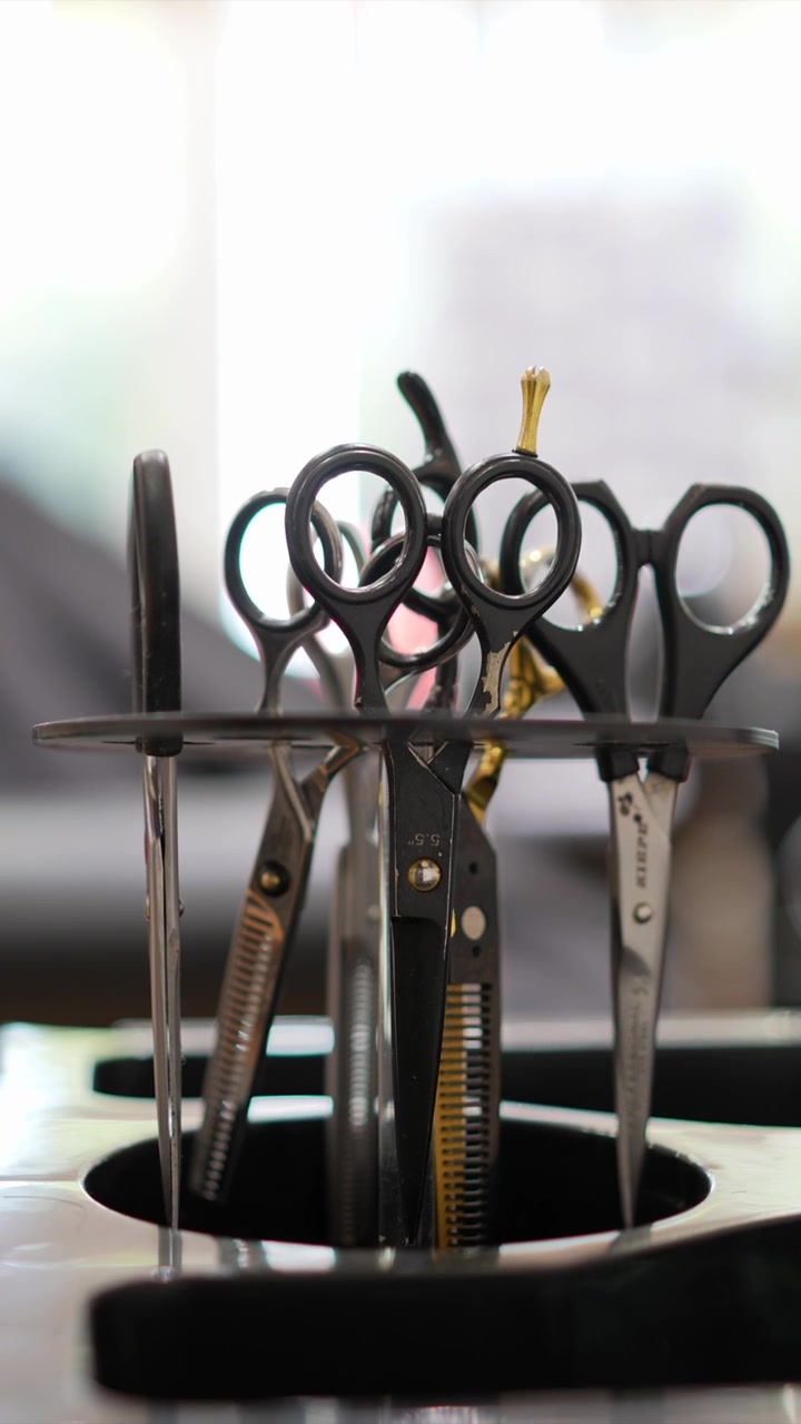 Hairdresser Selecting Professional Scissors from a Stand in a Salon