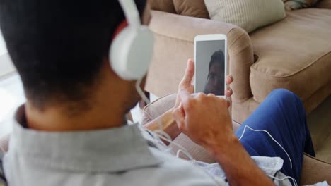 Happy-man-listening-music-on-mobile-phone-in-living-room