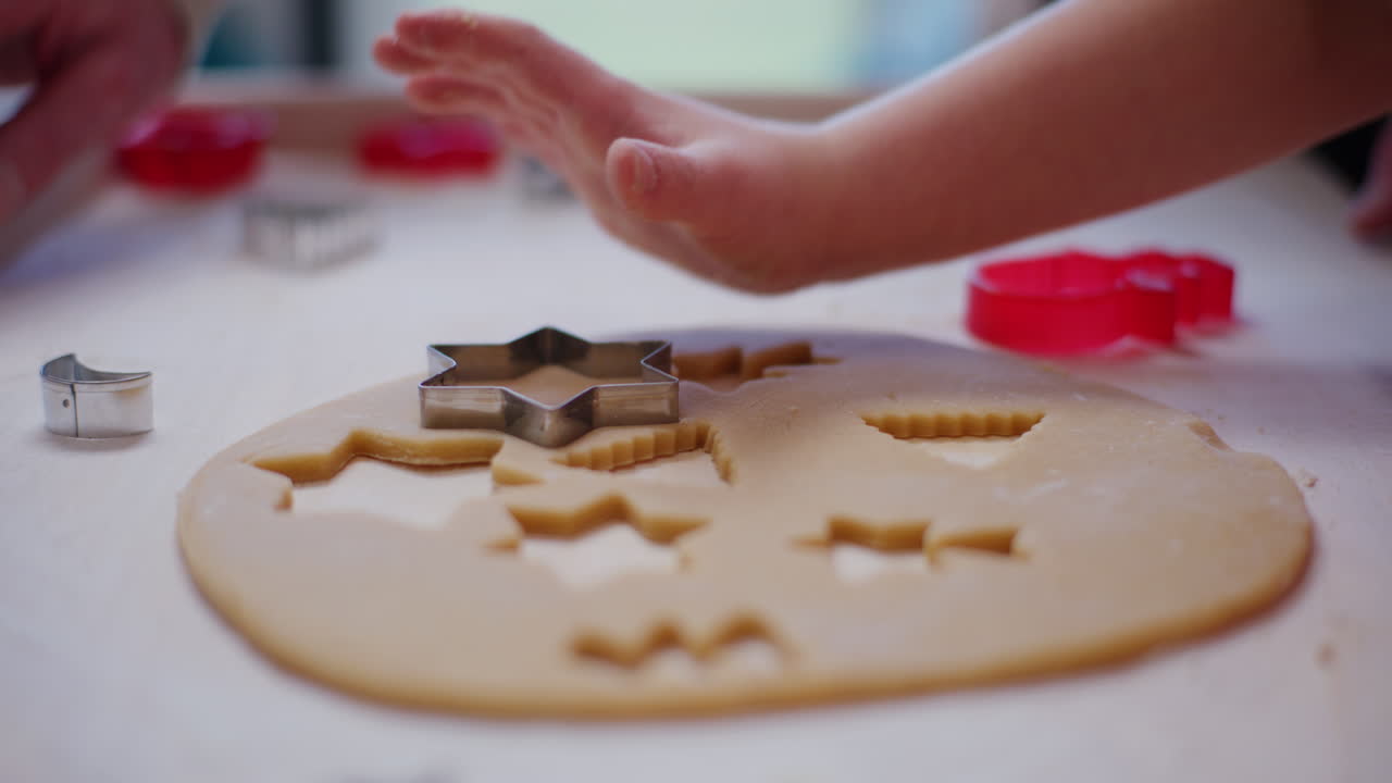 Nahaufnahme einer Jungenhand, die Plätzchen aus dem Teig aussticht.