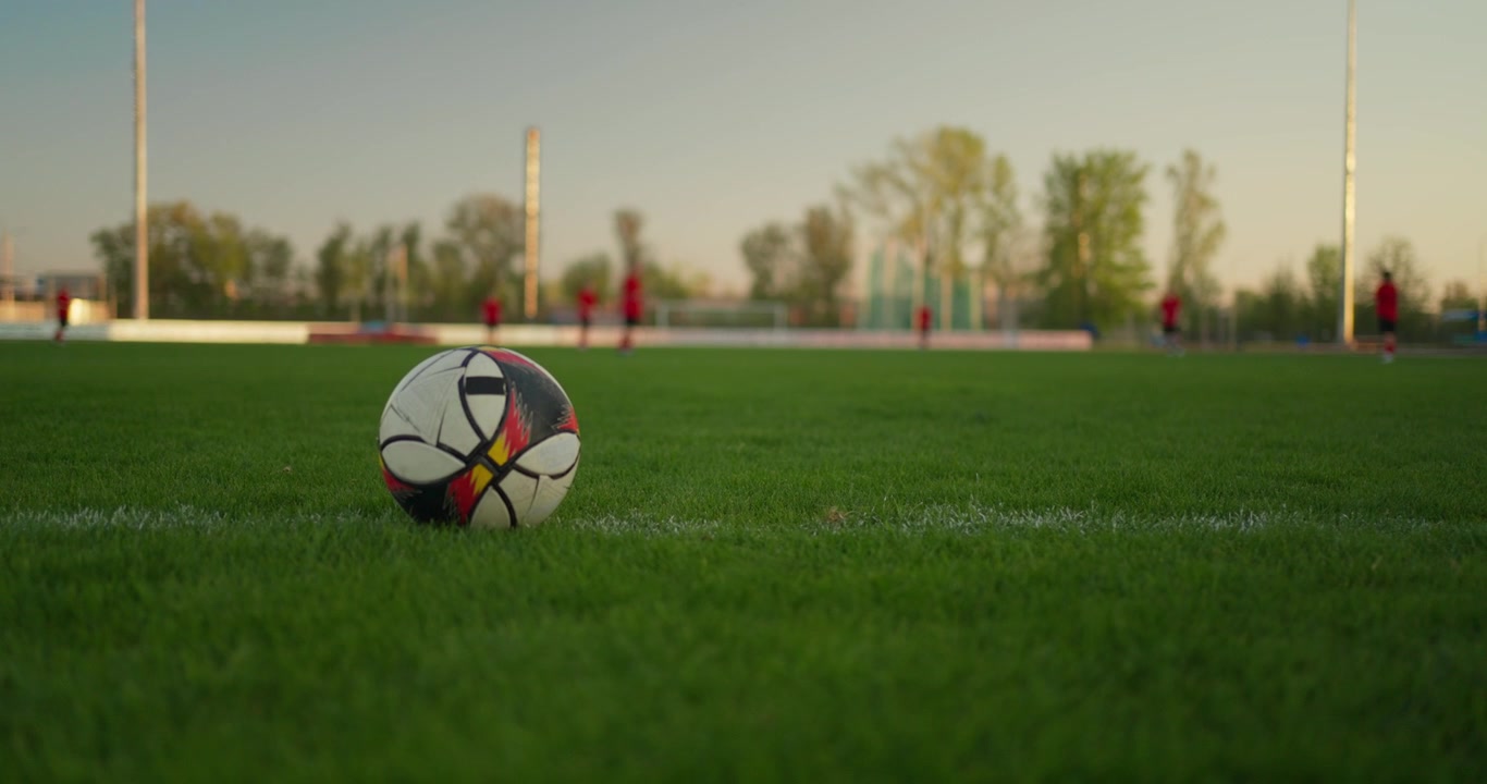 Nærbillede i slowmotion af fodboldspiller, der sparker bold på grøn bane