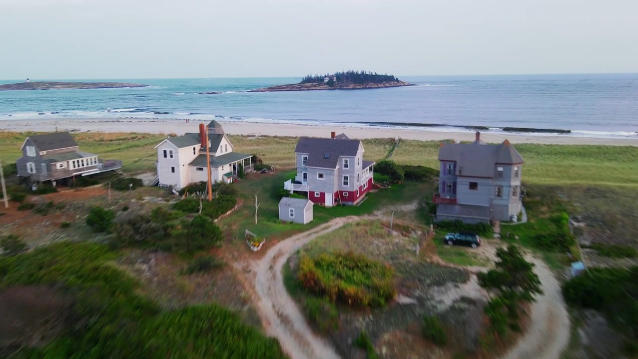Una ripresa aerea epica su ville costiere vittoriane sul mare e dune di sabbia con erba delle spiagge americana, che rivela Wood Island e la destinazione di vacanza incontaminata e appartata di Popham Beach a Phippsburg, Maine