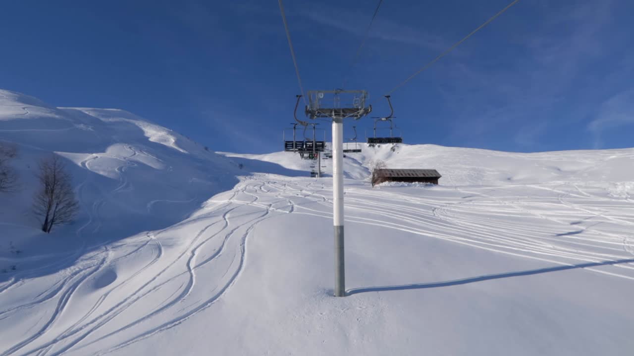 밝은 푸른 하늘과 하얀 신선한 눈이 있는 산속의 스키 리조트에서 체어리프트 타기