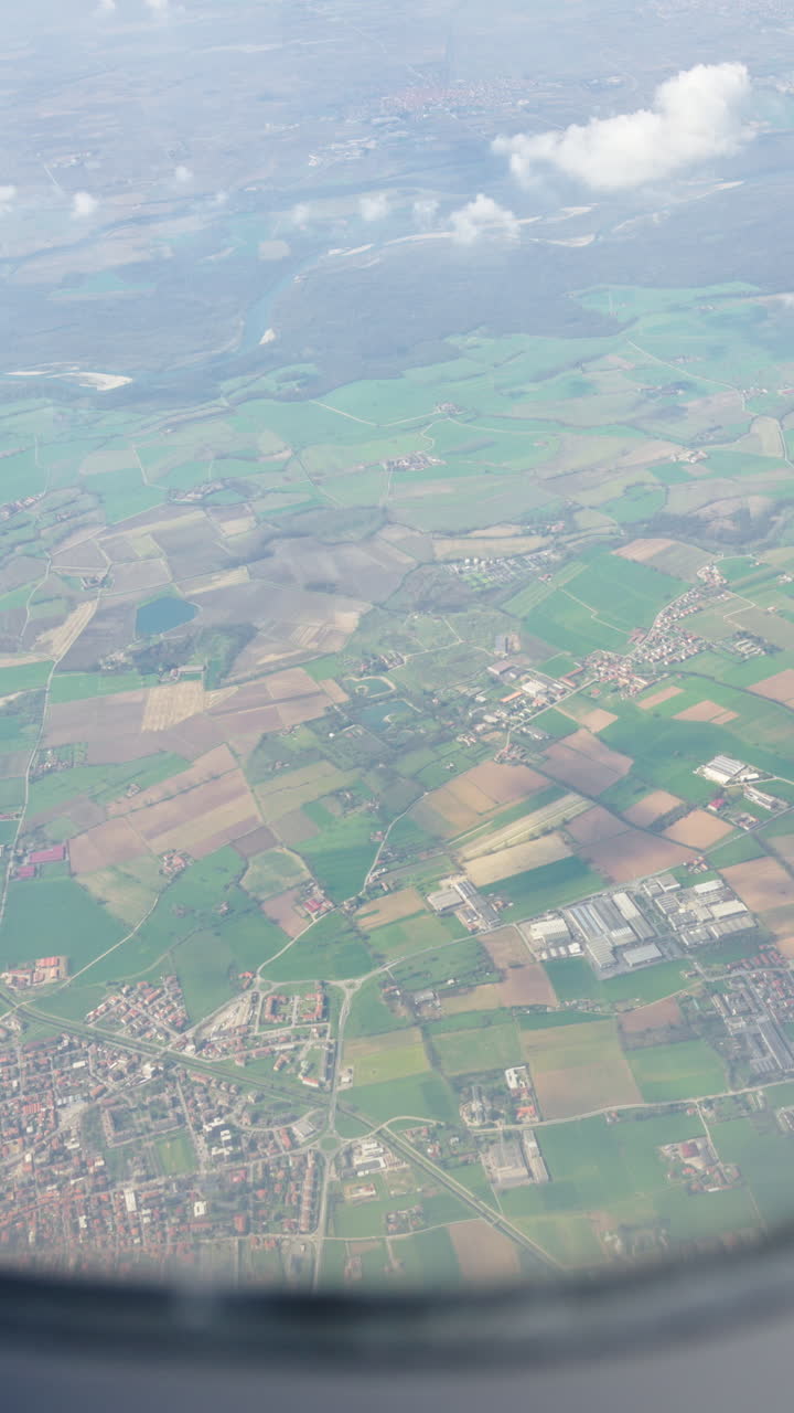 Aerial view of fields and towns from an airplane window. Vertical