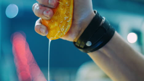 barman squeezing orange into glass during preparation of cocktail