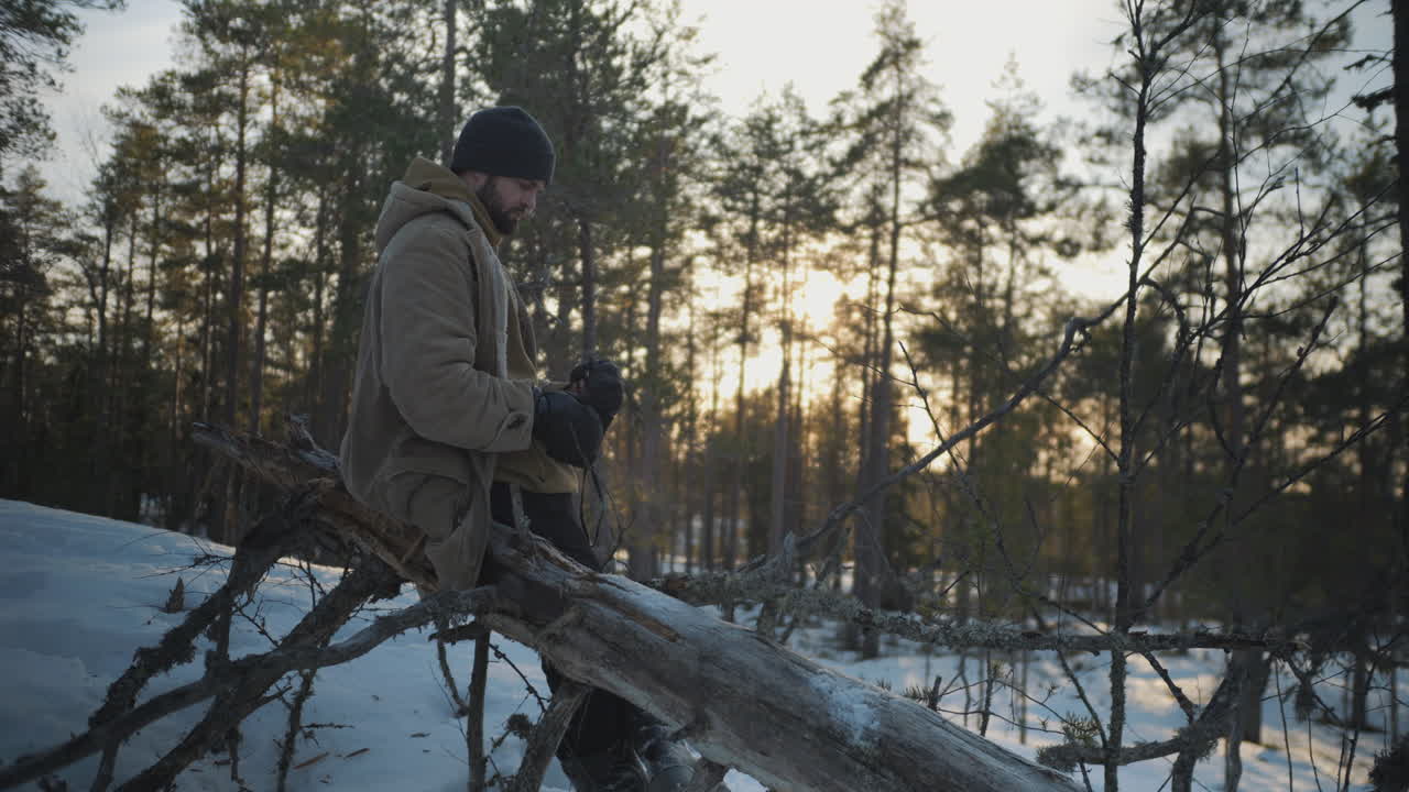 hombre observando pájaros con binoculares en la hora dorada, bosque de invierno cubierto de nieve