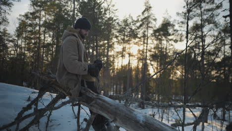 man birdwatching with binoculars at golden hour, winter forest covered with snow