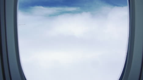 View-Through-Airplane-Window,-Sky-Over-The-Clouds---Flight-From-Australia-To-Singapore---aerial,-POV