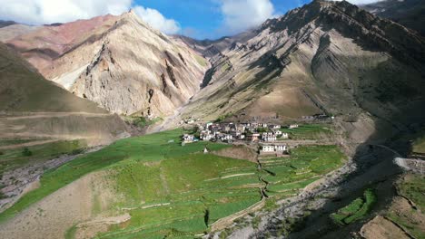 wide panoramic aerial of jagged rocky mountains surrounding mud village in pin valley on sunny summer day
