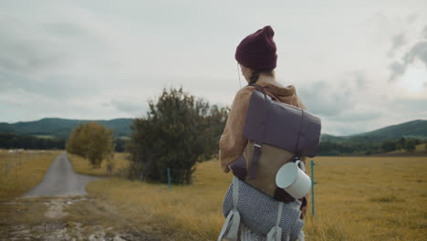 Female-tourist-with-backpack-walking-by-farm