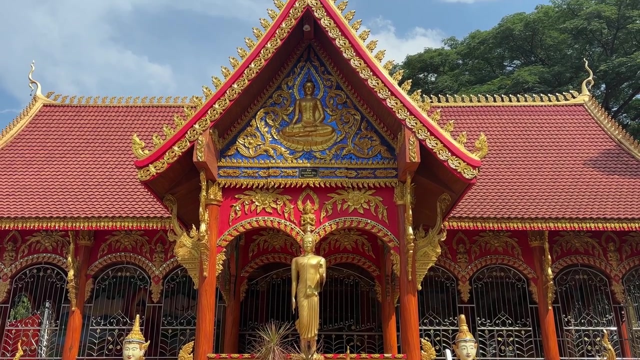 Fasad rumit kuil berwarna-warni di Laos dengan patung-patung detail.