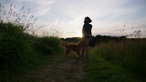 woman walking with her golden retriever on a nature trail at sunset, peaceful mood