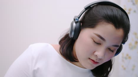 close up asian beautiful woman using the bluetooth headphone for listening to music so lovely lie in bed