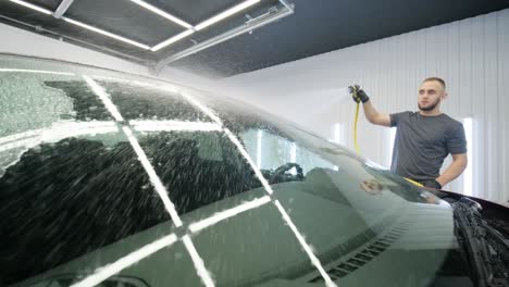 man worker washing red car on a car wash.