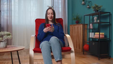 mujer joven adulta en casa usar teléfono móvil celular escribir navegación decir wow sí descubrió gran gran ganancia