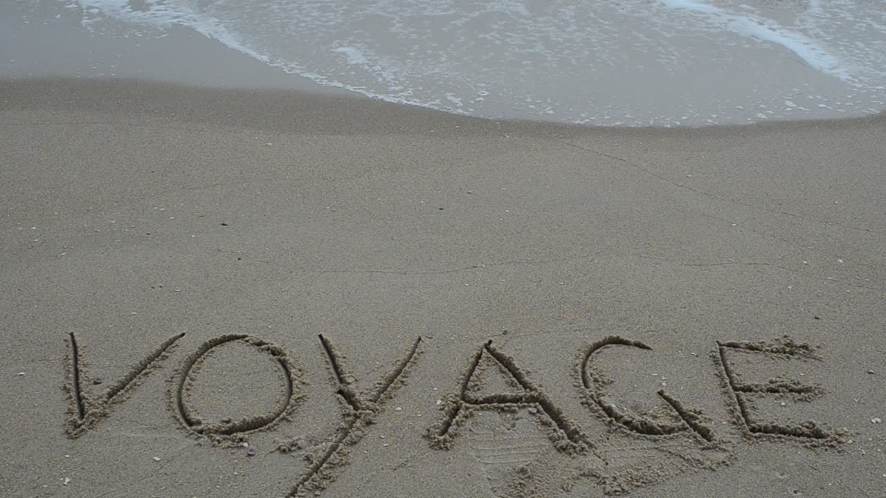 Inscription on wet sand voyage. Shooting on the beach
