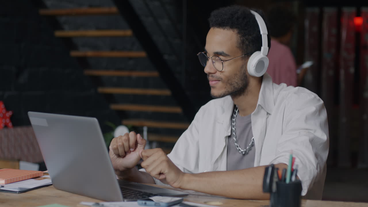 joven trabajando en una laptop con auriculares