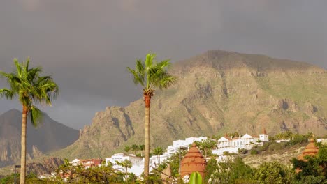 Beautiful-timelapse-of-fast-moving-clouds-at-Las-Americas-,-distant-mountains,-golden-hour-light-before-the-sunset,-palm-trees-in-foreground,-wide-shot