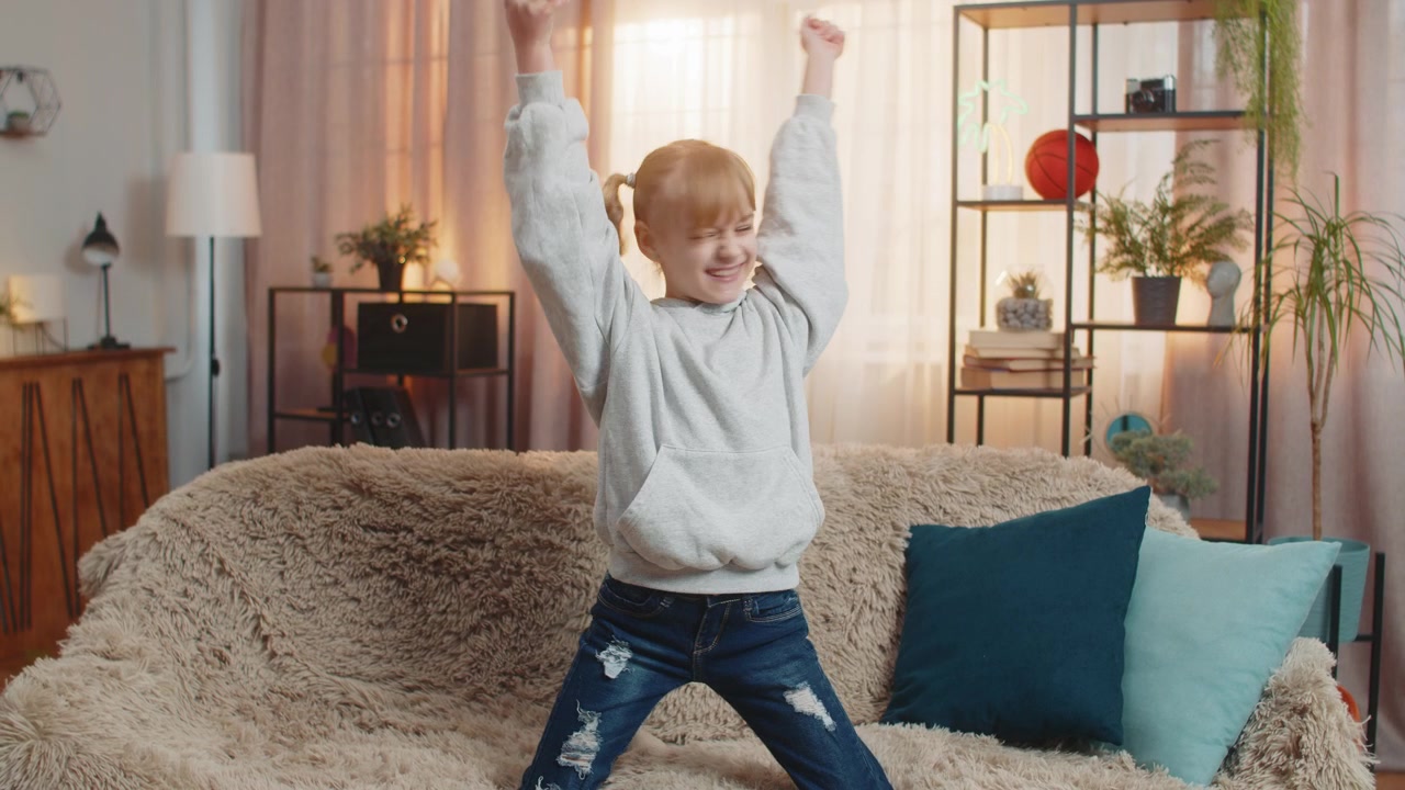 Young teenager girl playing mobile game at home sofa celebrate victory win cheerful triumph moment