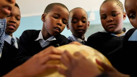 Schoolkids-using-globe-in-classroom-at-school-4k