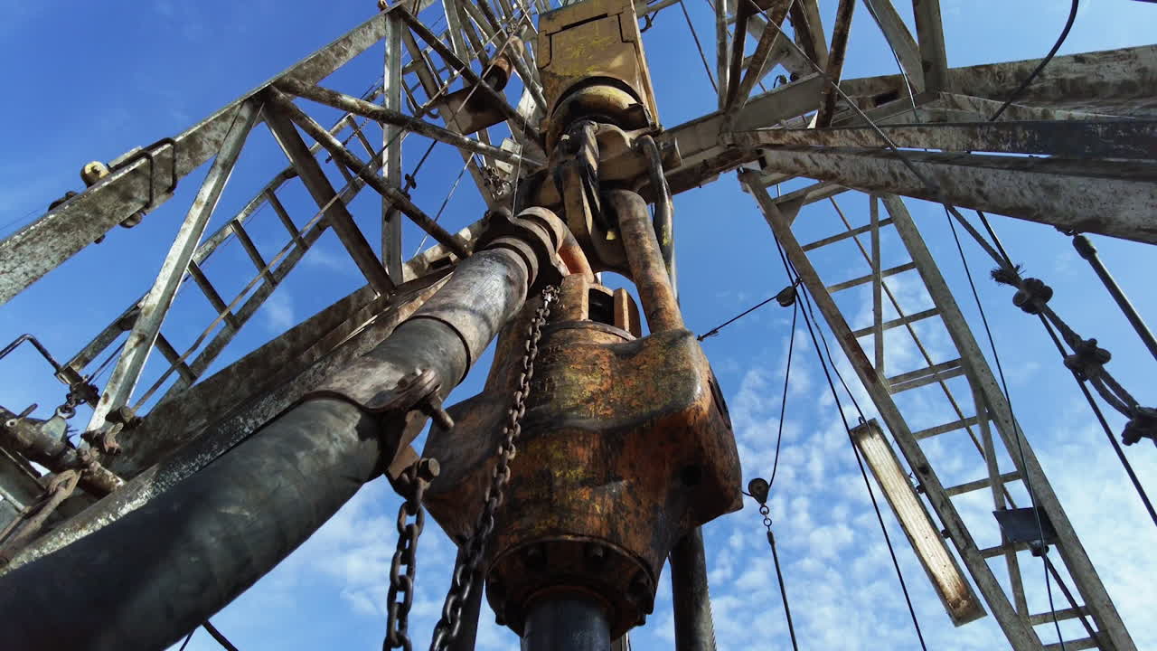Spinning borer drilling natural resources. Low angle view at the derrick producing oil.