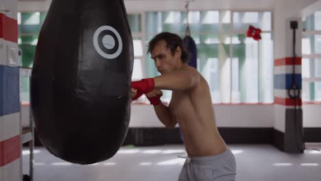 Caucasian-man-using-punchbag-in-boxing-gym