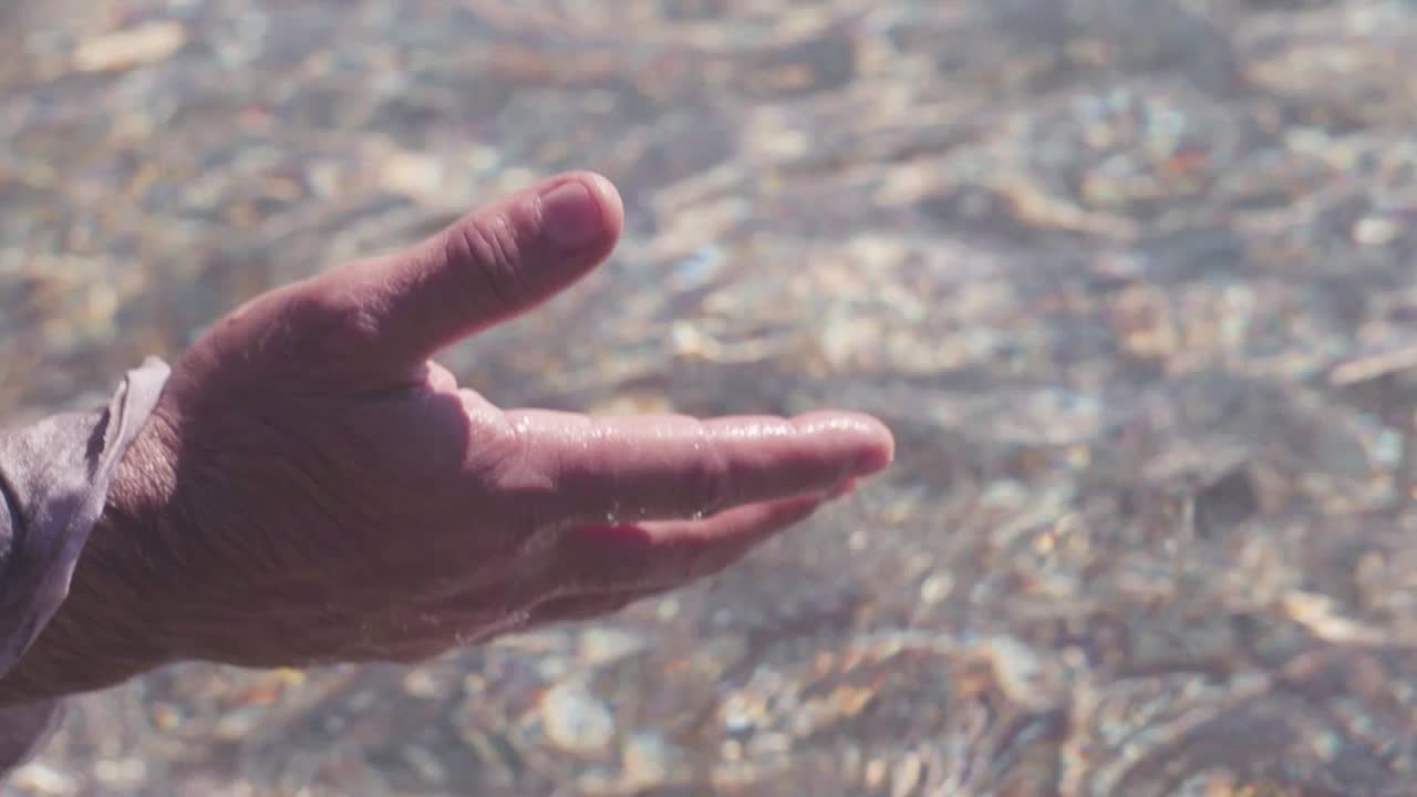 Child's Hand Holding Small Stones in Shallow Water