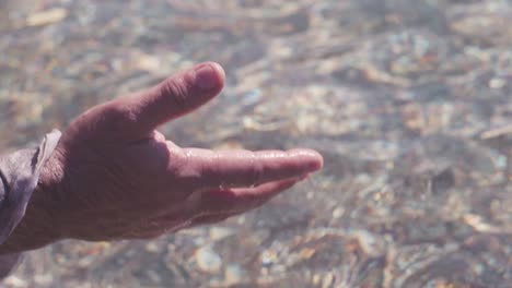 child's hand holding small stones in shallow water