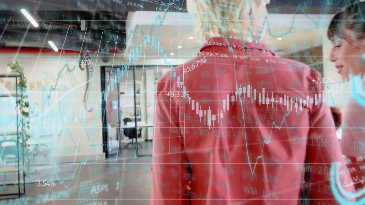 Two women walking office corridor, camera shift revealing finance chart onscreen, discussing market
