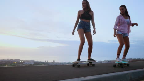 in slow motion, two friends wearing shorts ride skateboards along a road at sunset, with mountains and a captivating sky as the backdrop