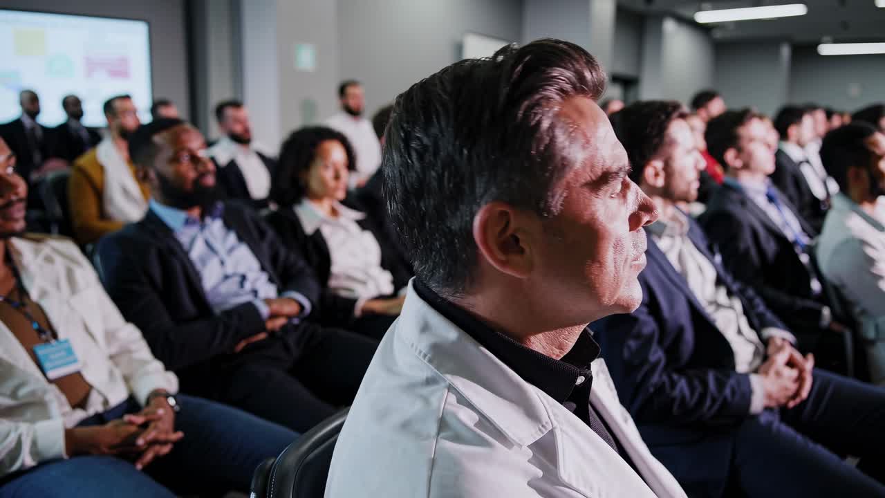 Una ripresa grandangolare cattura un seminario aziendale con i partecipanti concentrati su una presentazione