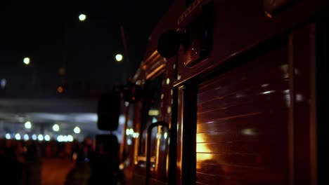 fire flames reflected on glossy red firetruck with flashing alarm emergency lights at night seoul, south korea - close-up