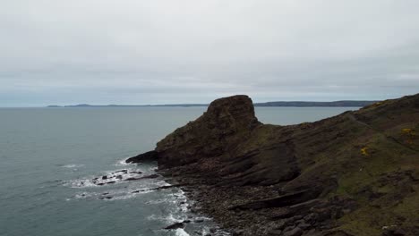 rickets head in pembrokeshire with crashing waves and rocky coastal cliffs - fast rising aerial drone shot uk 4k