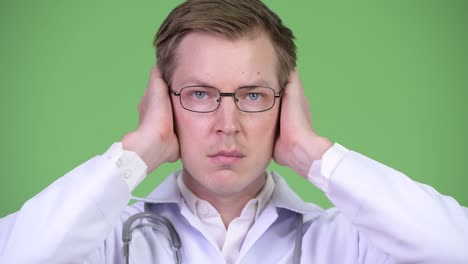 portrait of young man doctor covering ears