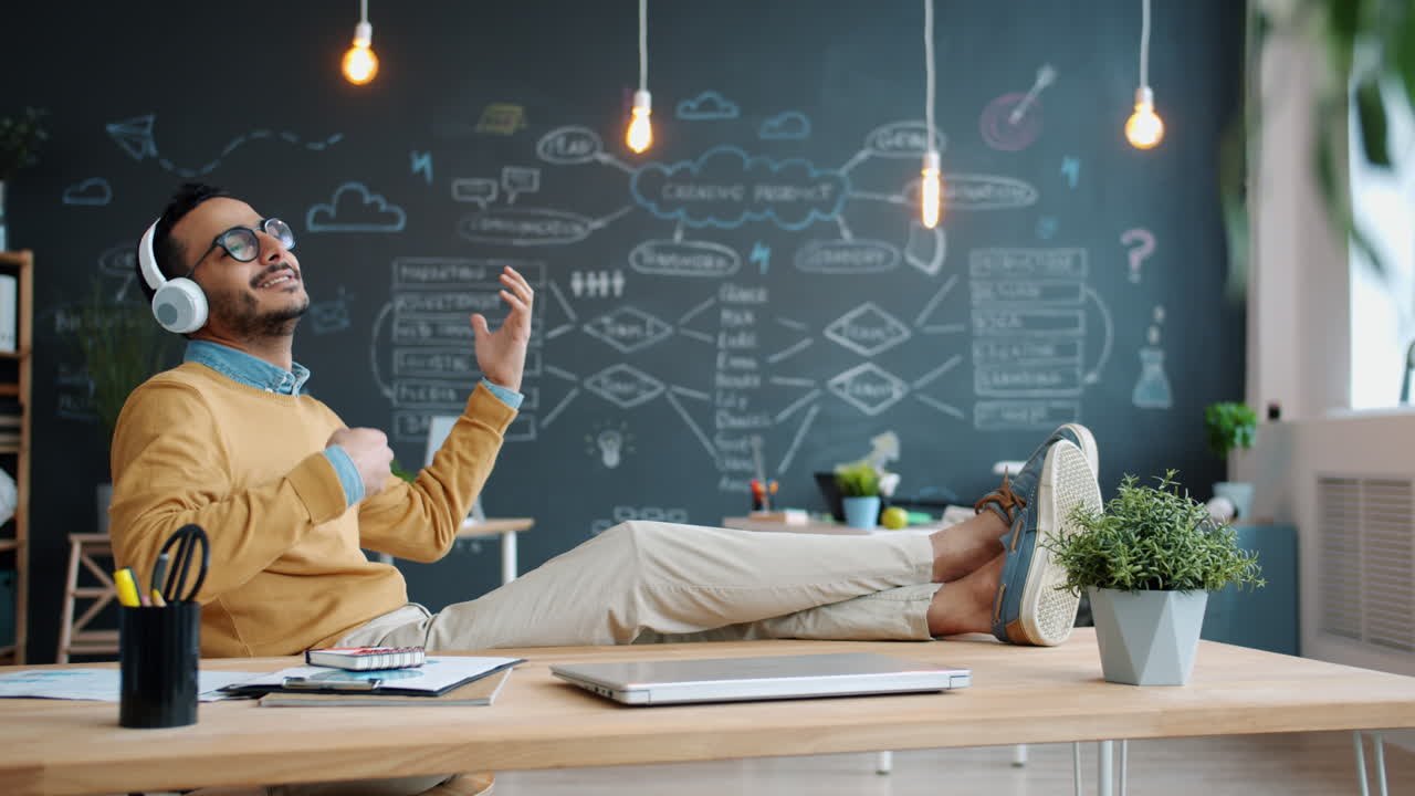 Man Relaxing at Desk, Listening to Music