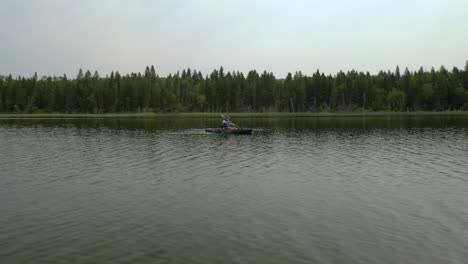 hombre en kayak en un lago tranquilo en el bosque boreal, saskatchewan, canadá