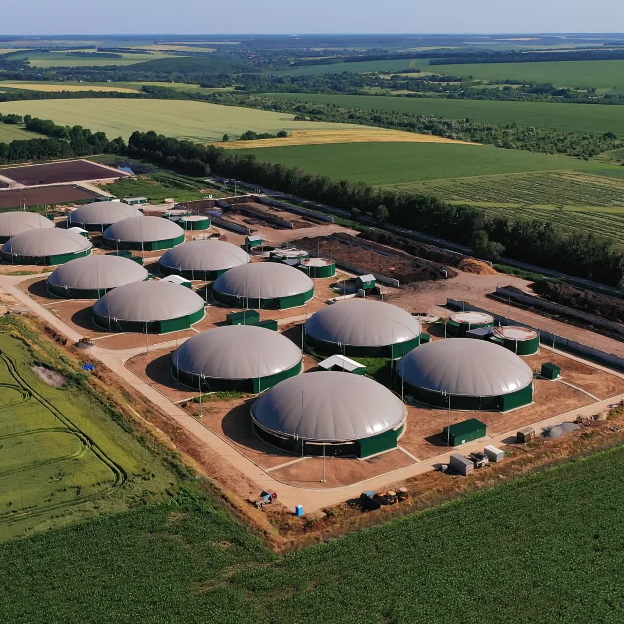 Biogas complex in the green plantations. Biogas storage tanks from the air perspective. Beautiful nature scenery at the backdrop