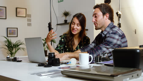 Photographers-discussing-over-laptop-at-desk-4k