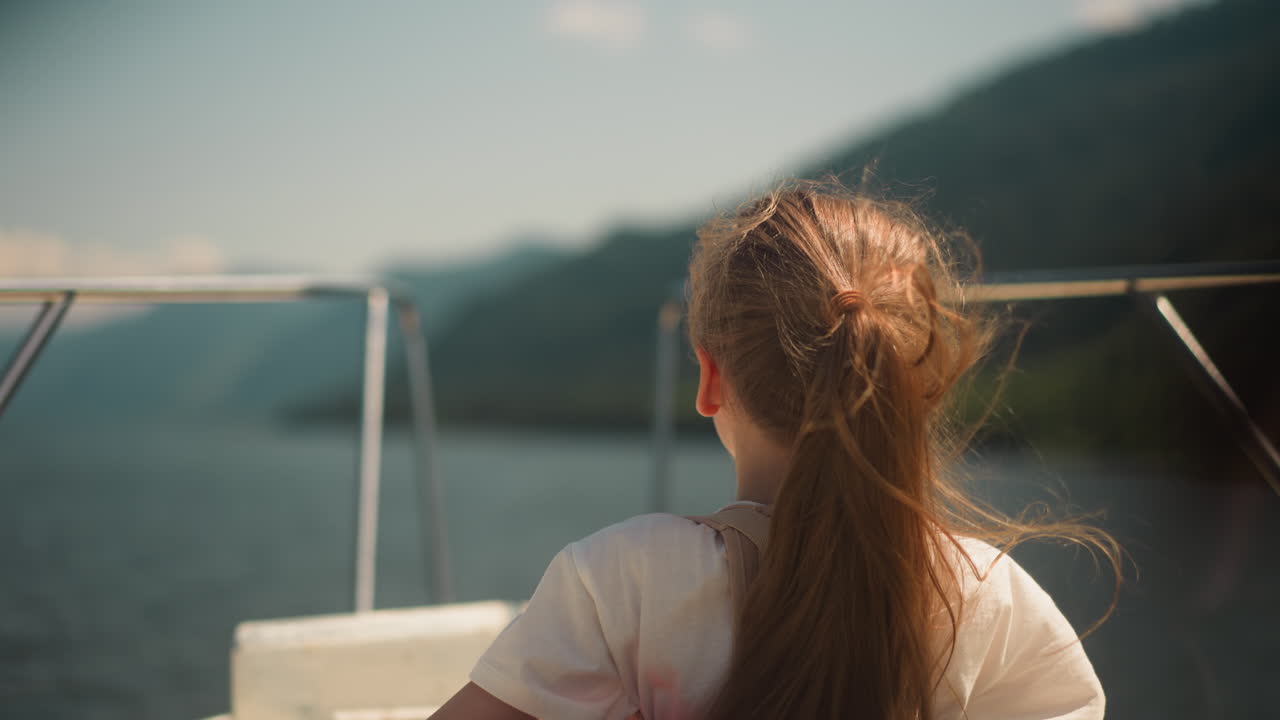 Little girl wearing scoliosis brace enjoys tourist boat rocking on ocean bay waves backside view. Child with back disease travels by yacht across sea
