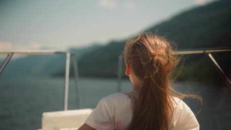 little girl wearing scoliosis brace enjoys tourist boat rocking on ocean bay waves backside view. child with back disease travels by yacht across sea