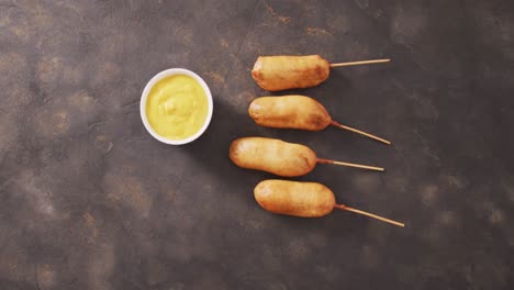 video of corn dogs with dip on a black surface