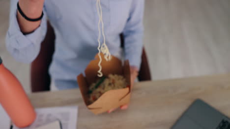 mujer comiendo fideos en el escritorio