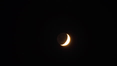 Time-lapsed-tracking-shot-of-crescent-moon-moving-through-a-darkening-sky-at-night-fall